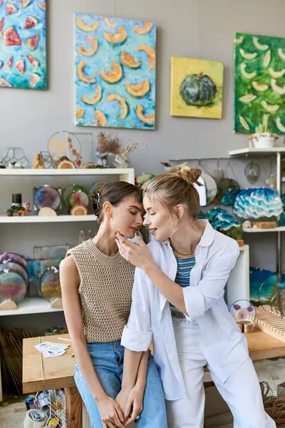 Deux femmes, un couple lesbien amoureux, admirent les peintures dans un atelier d'art. — Photo de stock