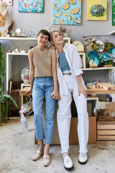 Two women, a romantic lesbian couple, standing together in an art studio. — Stock Photo
