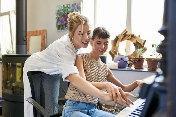 Una donna siede con la sua ragazza ad un pianoforte, condividendo un momento musicale. — Foto stock