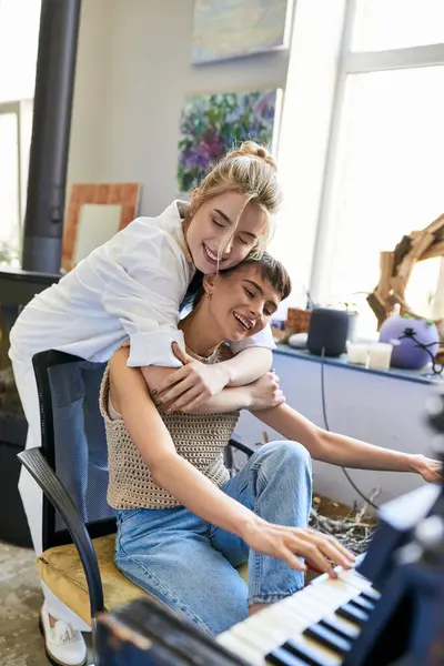 Woman sitting on piano next to her girlfriend in an art studio. — Stock Photo