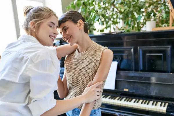 Две женщины стоят бок о бок, обнявшись музыкой фортепиано. — стоковое фото
