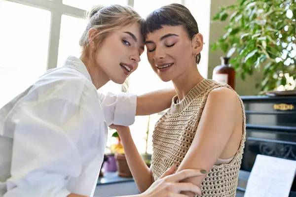 Two artistic women share a tender moment by the piano. — Stock Photo