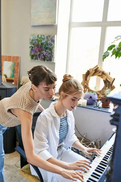 Lesbian couple playing piano in cozy art studio. — Stock Photo