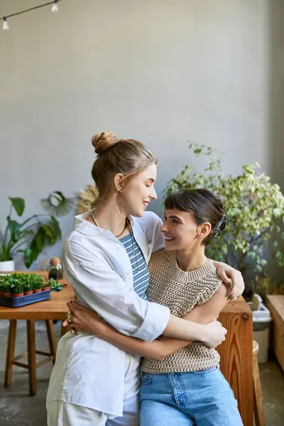 Two women, a loving lesbian couple, hug tenderly in an art studio. — Stock Photo