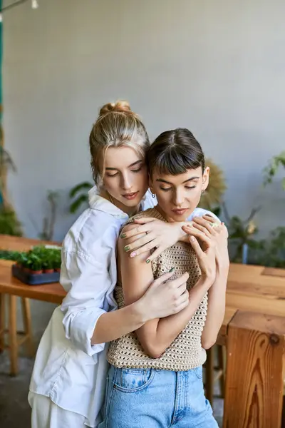 Due donne che si abbracciano teneramente in uno studio artistico. — Foto stock