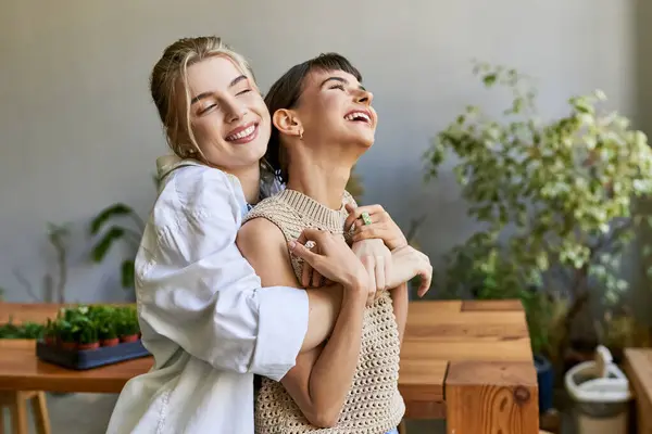 Two women lovingly embrace in an art studio. — Stock Photo