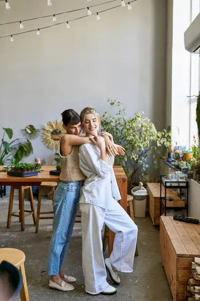 Two women standing side by side in an art studio, sharing a tender moment. — Stock Photo