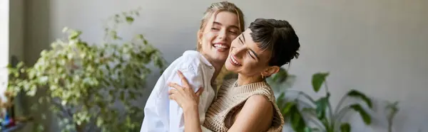 Two women, one blonde and one brunette, stand side by side in an art studio, sharing a loving moment. — Stock Photo