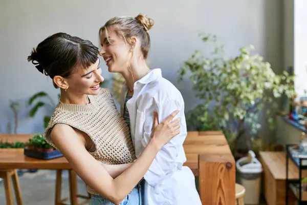 Two women, a loving lesbian couple, standing together in an art studio. — Stock Photo