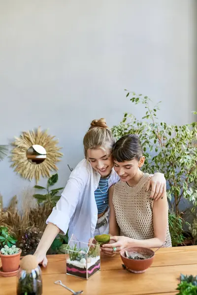 A loving tender lesbian couple sitting at a table with bowls of food at an art studio. — Stock Photo