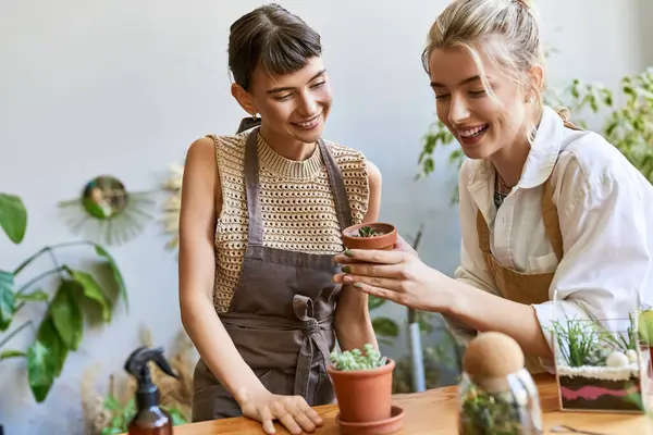 Dos mujeres admirando una planta en maceta con amor y curiosidad. - foto de stock