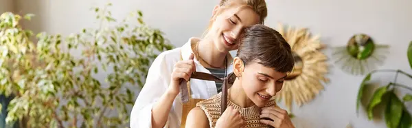 Loving lesbian couple in art studio, one woman brushing partners hair. — Stock Photo