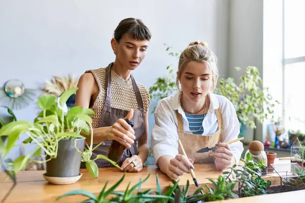Two women, a loving lesbian couple, sit at a table in an art studio. — Stock Photo