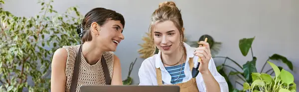 Deux femmes à table se concentrent sur l'ordinateur portable, collaborant et créant de l'art ensemble. — Photo de stock