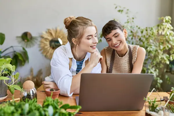 Artistic lesbian couple engrossed in laptop at studio table. — Stock Photo