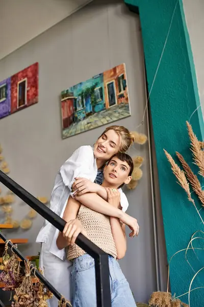 Deux femmes, un couple lesbien amoureux, partageant un câlin tendre dans un espace artistique. — Photo de stock