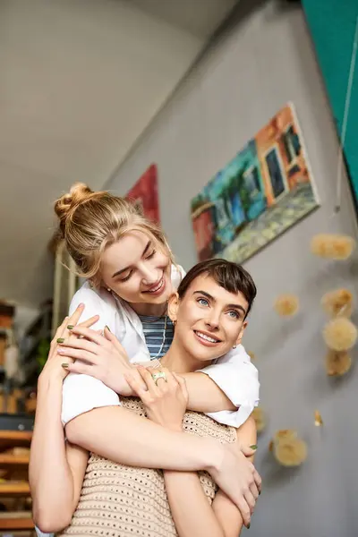 Zärtliche Umarmung zwischen zwei Frauen, von denen eine die andere in einem Kunstatelier in den Armen hält. — Stockfoto