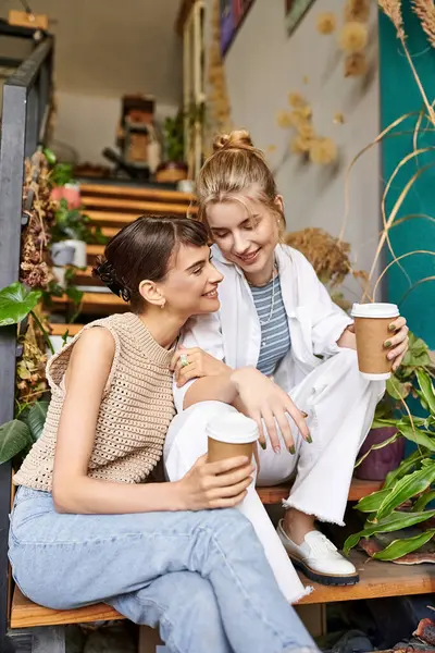 Deux femmes dégustant un café sur un banc dans un studio d'art. — Photo de stock