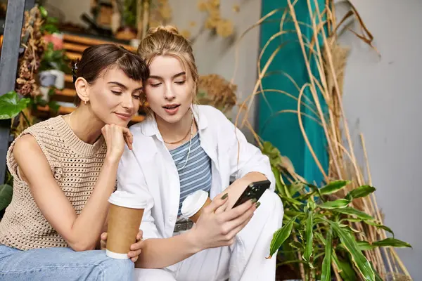 Tender lesbian couple share a moment, engrossed in cell phone. — Stock Photo