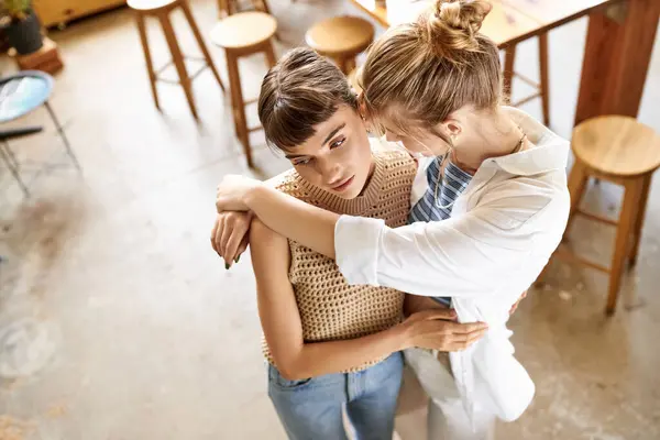 Two women in art studio sharing a tender embrace. — Stock Photo