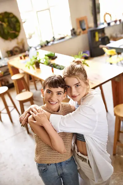 Two women, a loving tender lesbian couple, embracing in an art studio. — Stock Photo