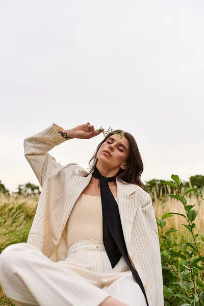 Une jeune femme en tenue blanche assise paisiblement dans un champ luxuriant, trempant dans la brise d'été et la sérénité. — Photo de stock