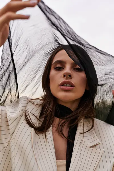 Uma jovem elegante em um terno fica em um campo, segurando um guarda-chuva como ela gosta da brisa de verão. — Fotografia de Stock