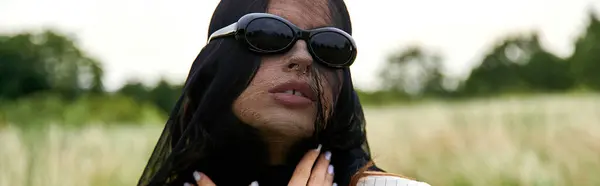 Таинственная женщина в черной вуали и солнечных очках излучает элегантность и изысканность в естественной обстановке. — стоковое фото