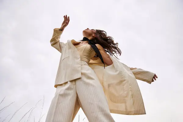 Une belle jeune femme en costume blanc vole gracieusement dans les airs, embrassant la brise d'été dans un champ serein. — Photo de stock