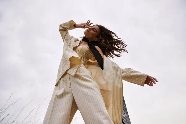 A beautiful young woman in a white suit and black tie, embracing the summer breeze in a field of nature. — Stock Photo
