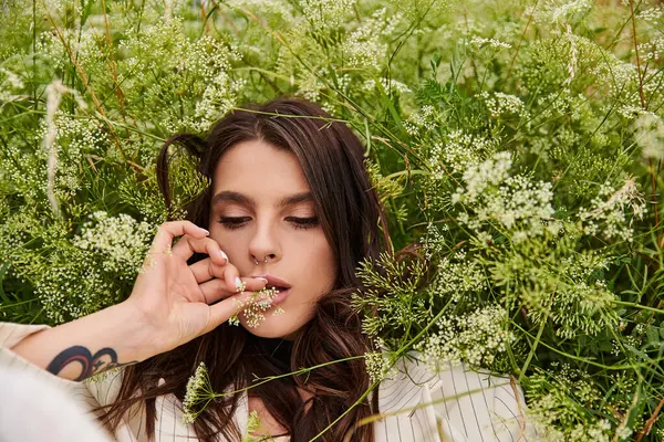 Eine junge Frau in weißer Kleidung entspannt sich in einem Blumenfeld und genießt die sommerliche Brise. — Stockfoto