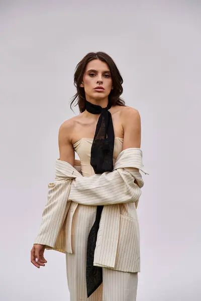 A beautiful young woman in a white dress and black tie stands gracefully in a field, enjoying the summer breeze. — Stock Photo