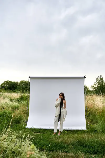 Una joven se levanta con gracia frente a una pantalla blanca, encarnando una sensación de elegancia y serenidad en un entorno natural. - foto de stock