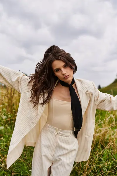 A beautiful young woman in white attire stands in a field, arms outstretched, embracing the summer breeze. — Stock Photo