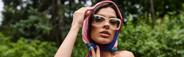 Una hermosa joven con una bufanda alrededor de su cabeza, disfrutando de una brisa de verano en la naturaleza. - foto de stock