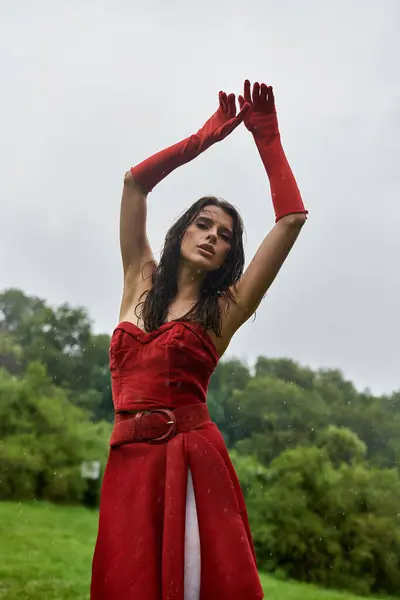 Une jolie jeune femme en robe rouge et de longs gants profitant de la brise estivale dans la nature. — Photo de stock