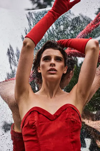 An elegant woman in a flowing red dress and long gloves, embracing the summer breeze in a natural setting. — Photo de stock