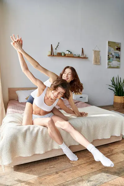 Beautiful lesbian couple in comfy attire sitting on a bed together. — Stock Photo