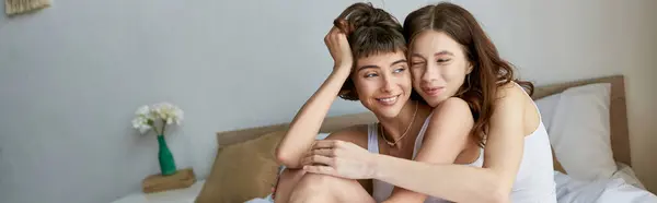 A beautiful lesbian couple in comfy attire enjoying a cozy moment on a bed. — Stock Photo