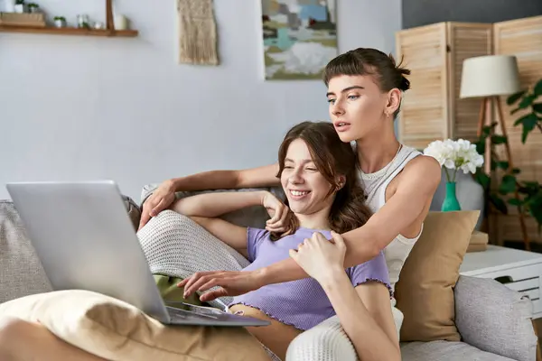 Two women enjoy a cozy moment on the couch while using a laptop. — Stock Photo