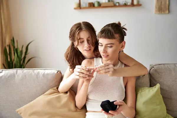 Two women in comfy attire sitting on a couch, engrossed in ring. — Stock Photo