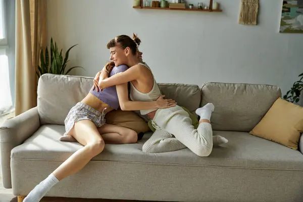 Duas mulheres em trajes confortáveis sentam-se em cima de um sofá, desfrutando uma da outra companhia. — Fotografia de Stock