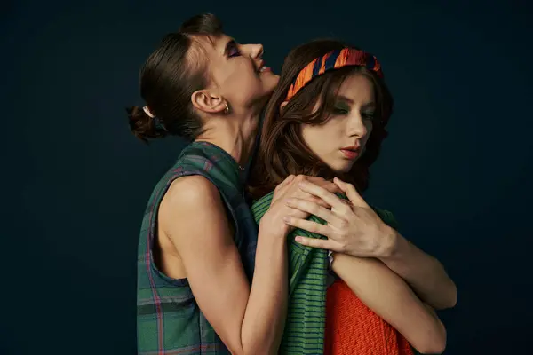 Deux femmes en tenue décontractée s'embrassent, debout côte à côte avec leurs bras autour de l'autre. — Photo de stock