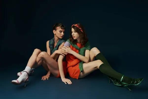 Two women in relaxed attire sit closely together, sharing a quiet moment of companionship. — Stock Photo