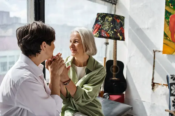 A mature lesbian couple standing together in front of a window. — Stock Photo