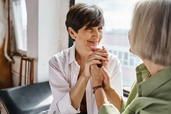 A woman sits beside her partner, who gently holds her hands together. — Stock Photo