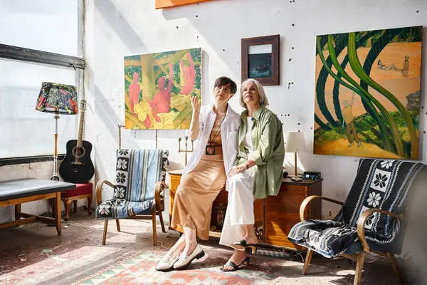 Due donne esplorano insieme una stanza piena d'arte. — Foto stock