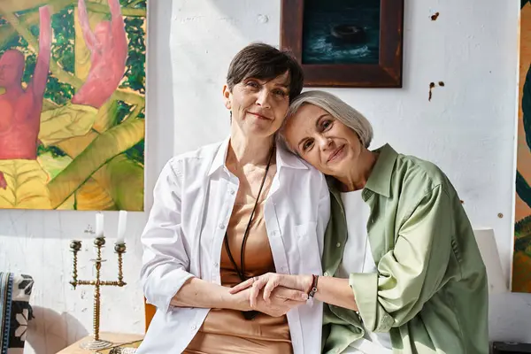 Two mature lesbian women, serenely sitting together in an art studio. — Stock Photo