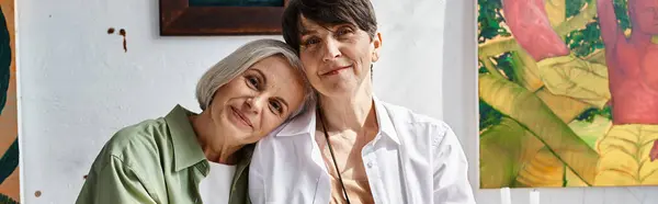 A mature lesbian couple sitting together in an art studio. — Stock Photo