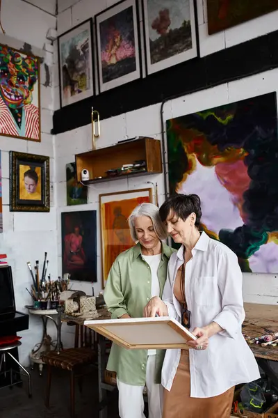 Mature couple lesbien paisiblement debout ensemble dans un studio d'art. — Photo de stock